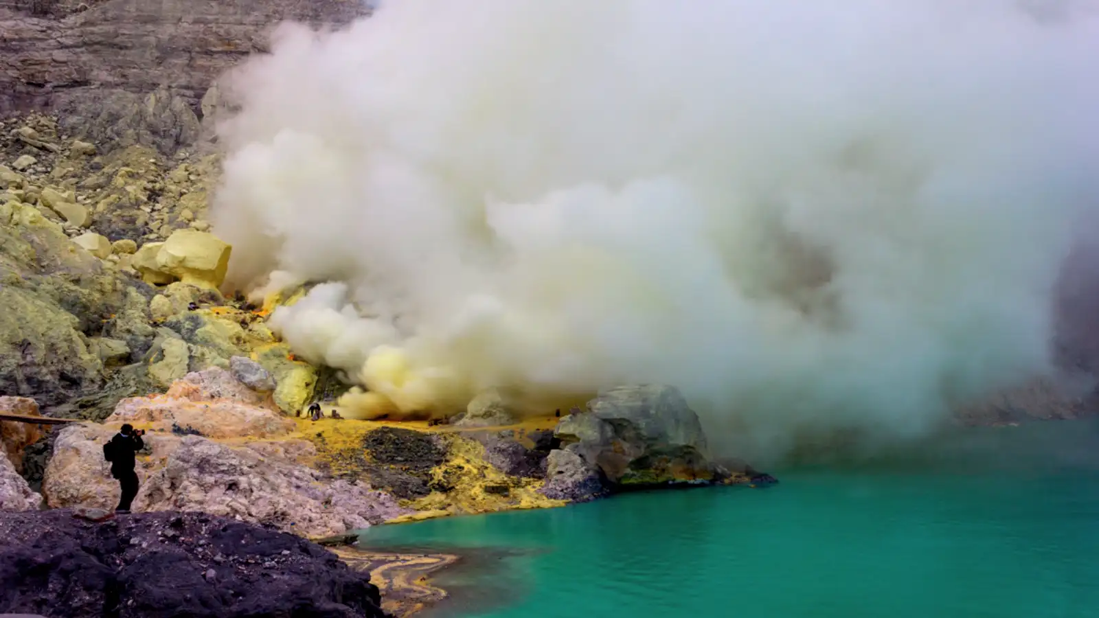 Hikers trekking up the steep slopes of Mount Ijen towards the crater rim at sunrise