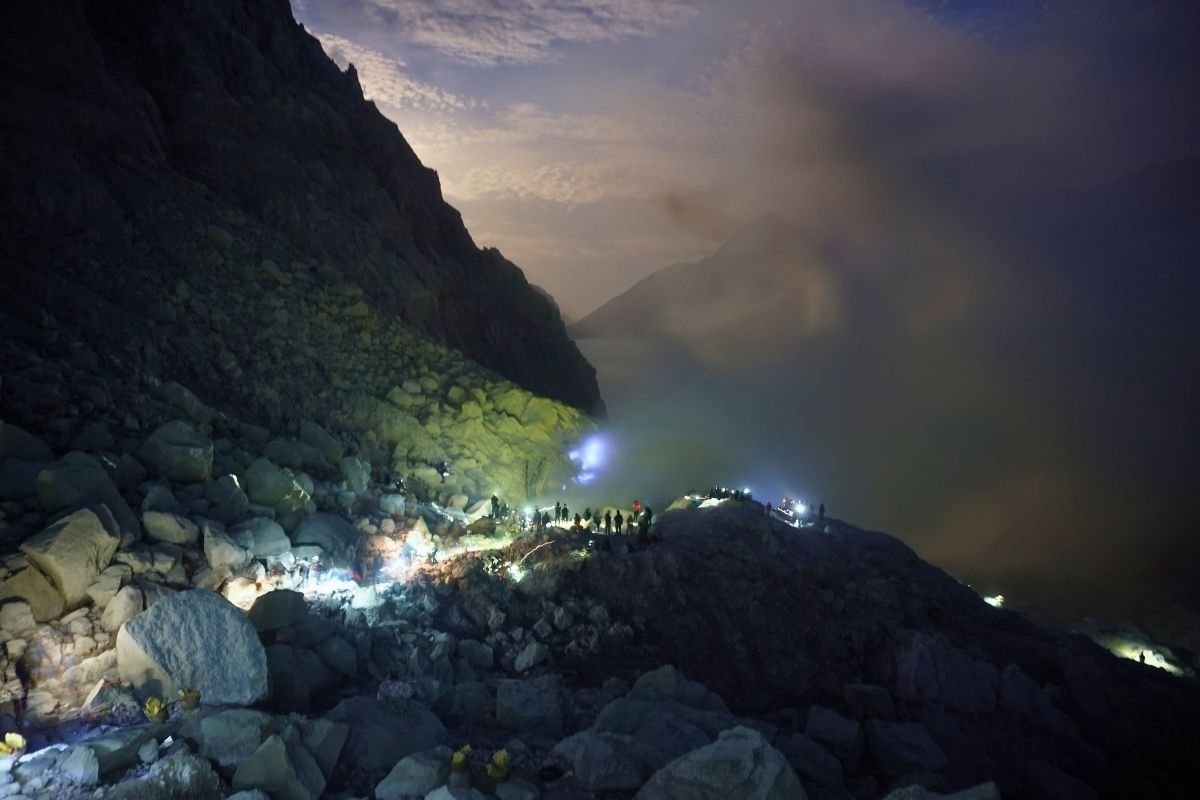 Hikers using headlamps walking uphill during Ijen night trekking