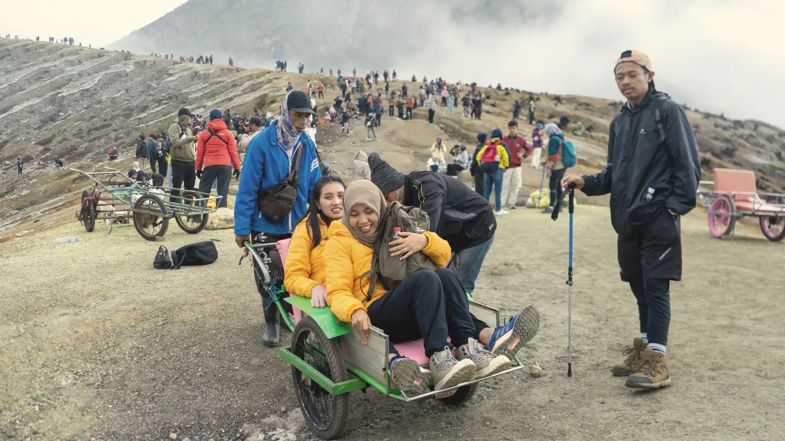 Sulfur miners pushing an Ijen trolley taxi up the steep volcanic trail at sunrise