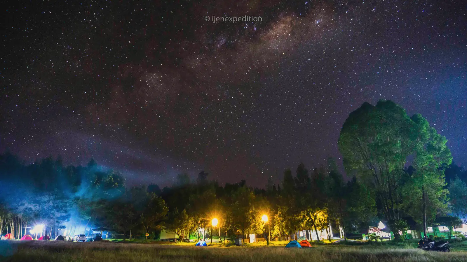 Photographer with a tripod overlooking the Ijen crater under the Milky Way