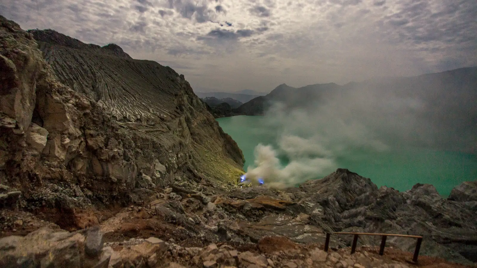 Hiker overlooking the massive Ijen Crater lake at sunrise