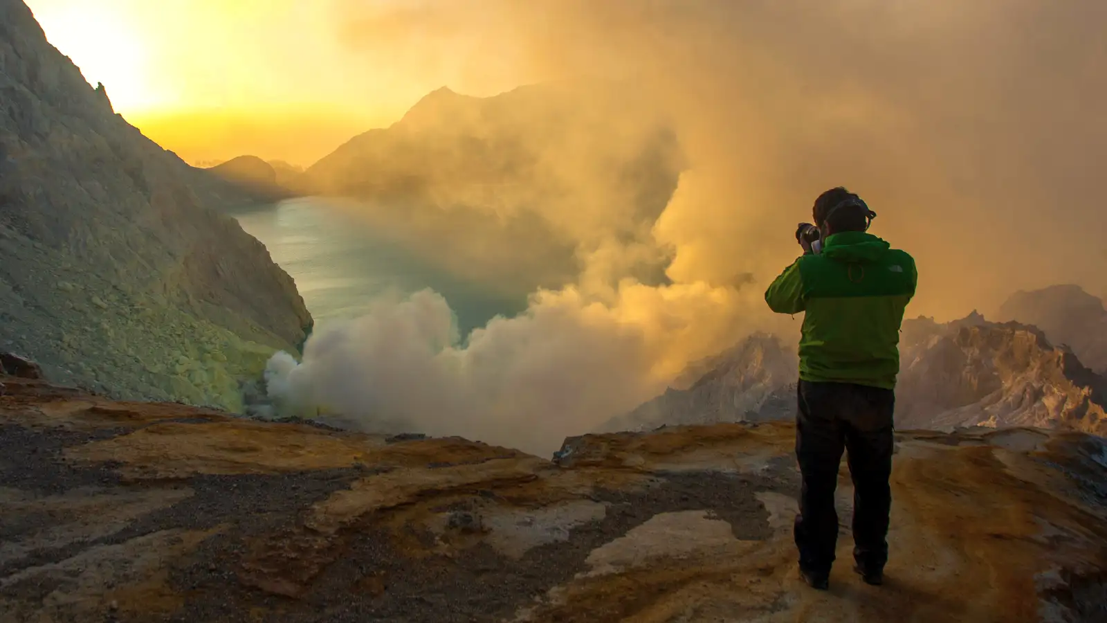 Turquoise acidic lake of Ijen Crater at sunrise with volcanic steam