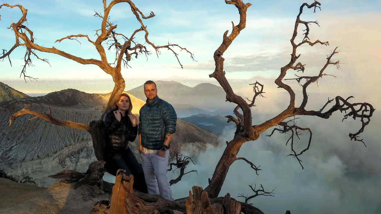 Photographer standing at the Dead Tree Viewpoint overlooking Ijen Crater at sunrise