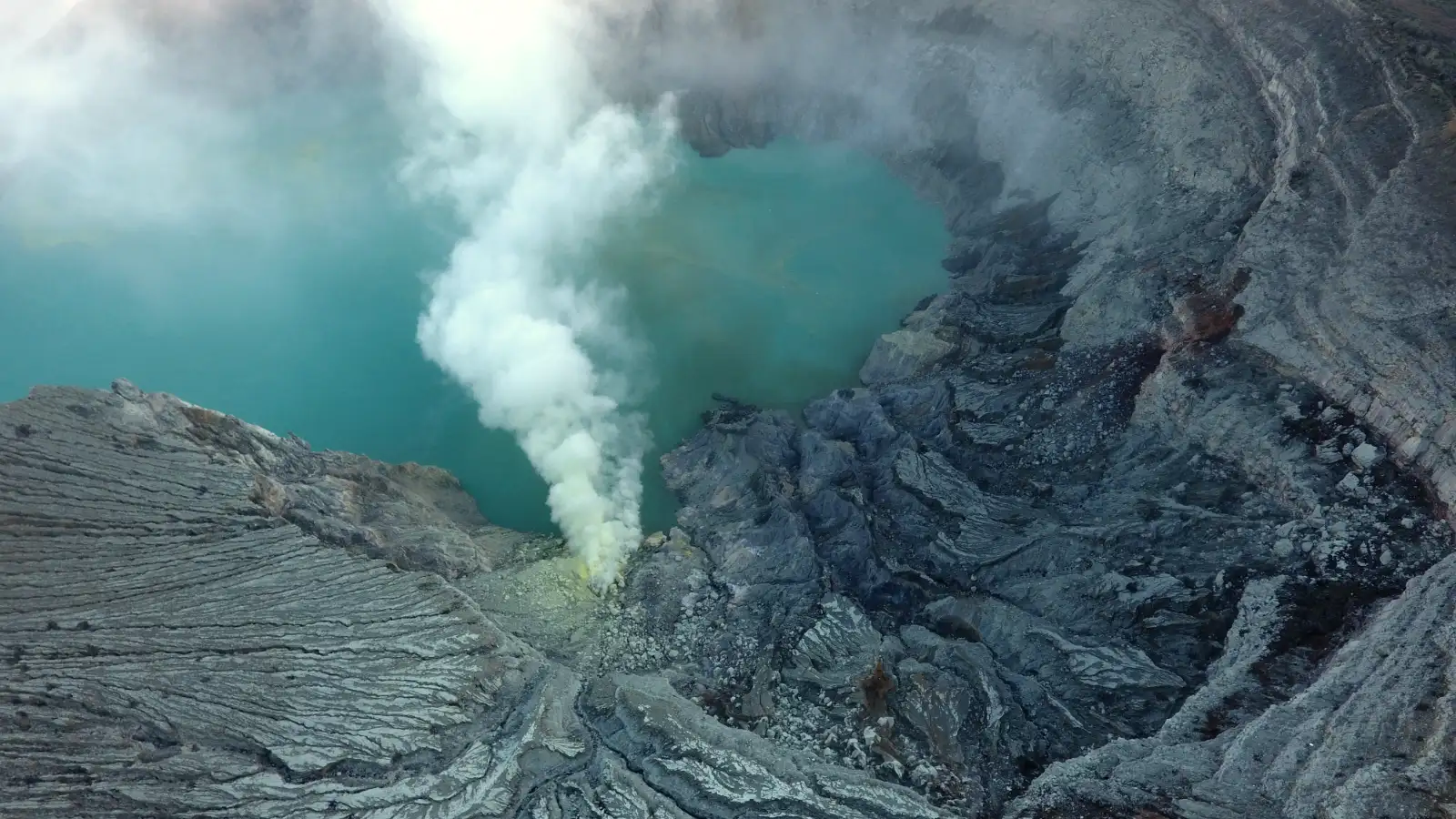 Landscape of Ijen Crater with yellow sulfur rocks and turquoise water
