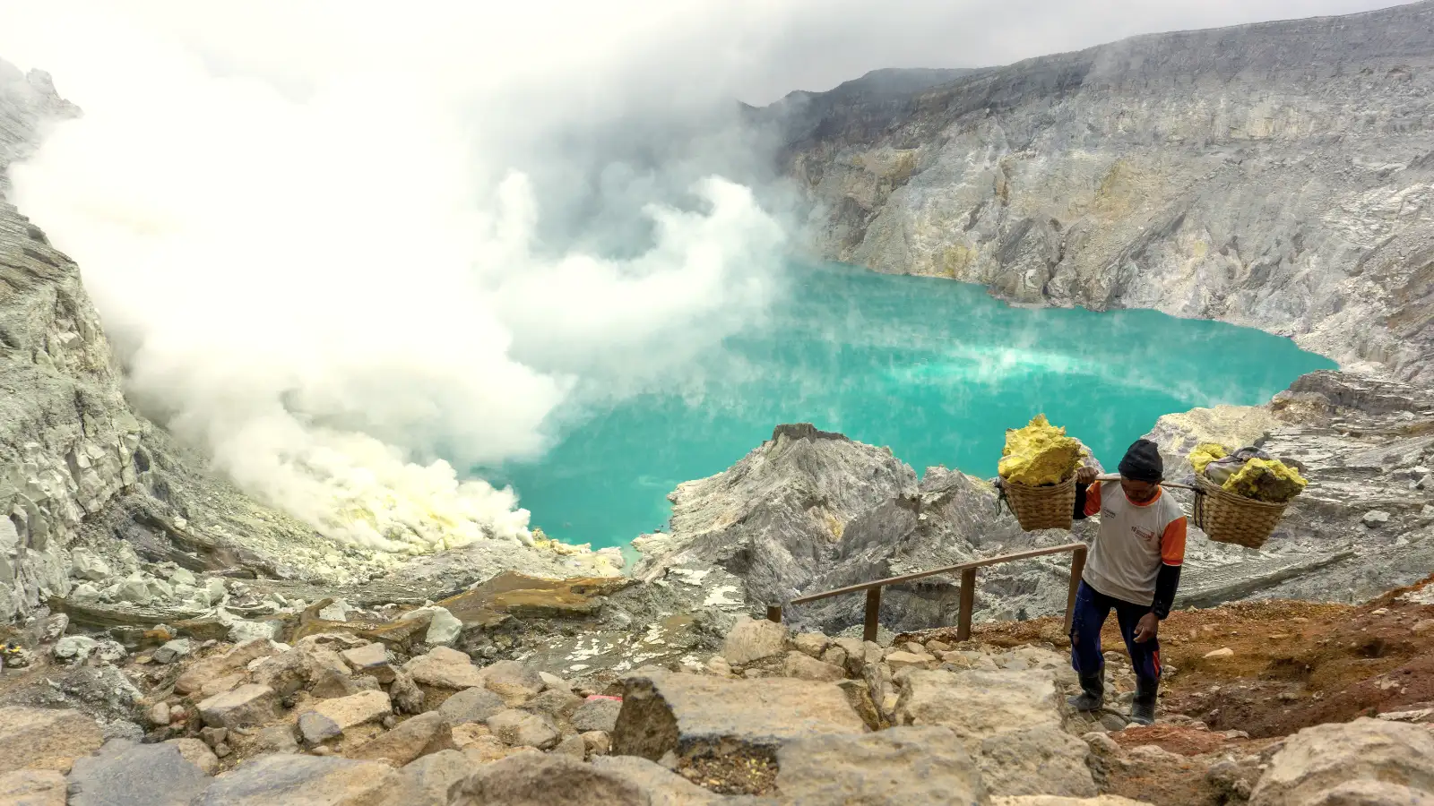 The turquoise acidic lake of Ijen Crater during daytime with sulfur clouds