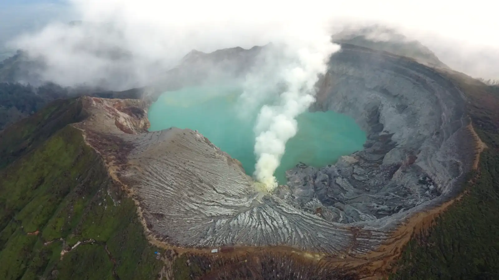 Aerial view of Ijen Crater turquoise acid lake with sulfur smoke
