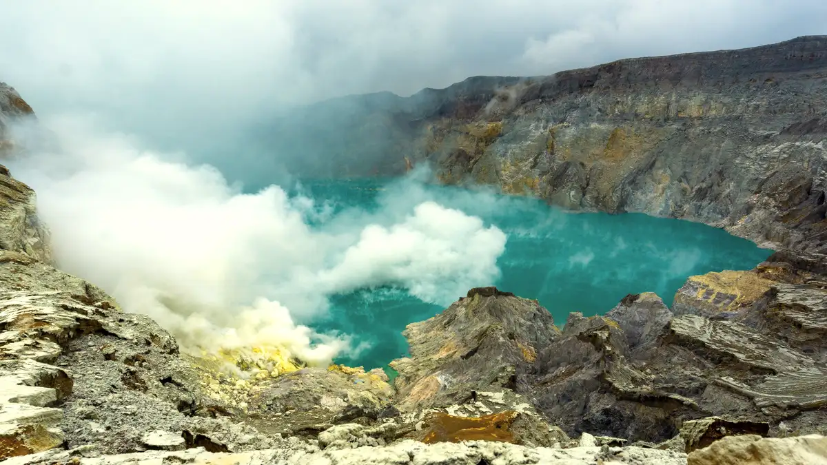Elderly travelers and hikers facing the sulfur smoke at Ijen Crater