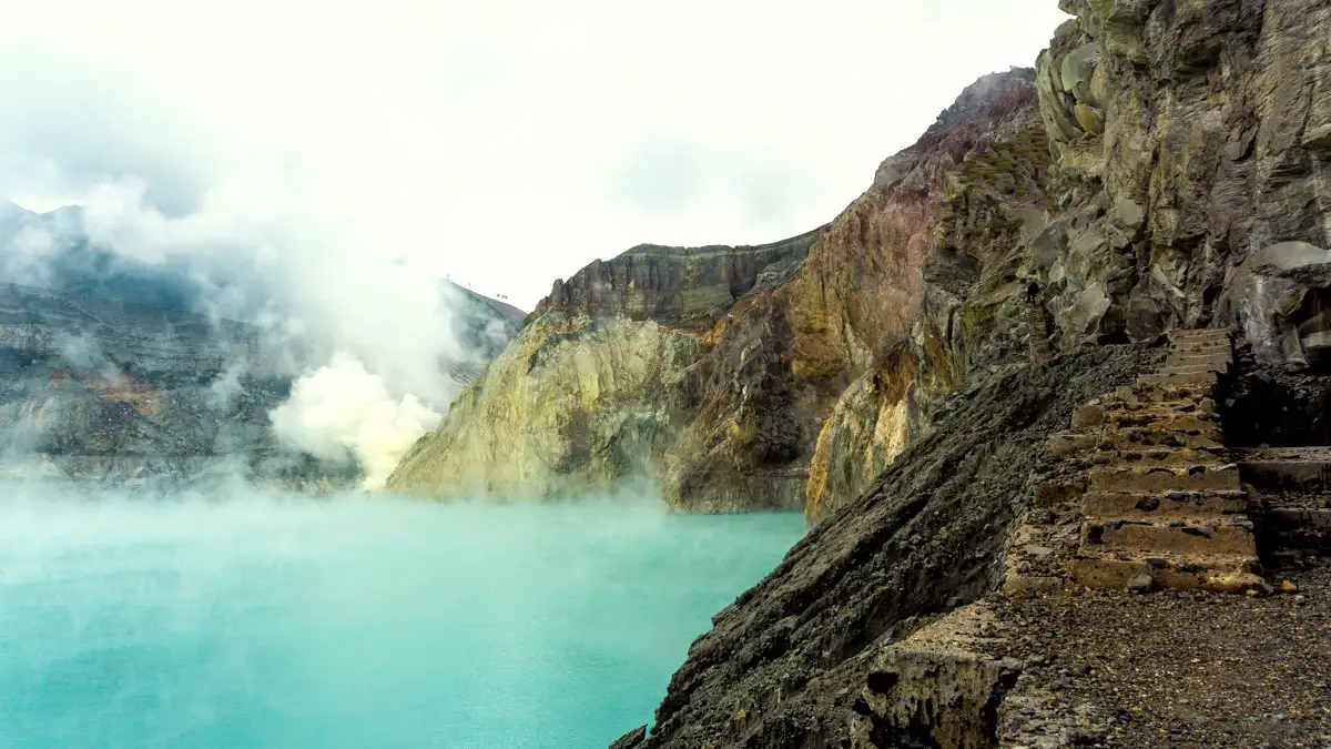 Beginner hikers trekking the Mount Ijen trekking path at sunrise with turquoise acid lake views