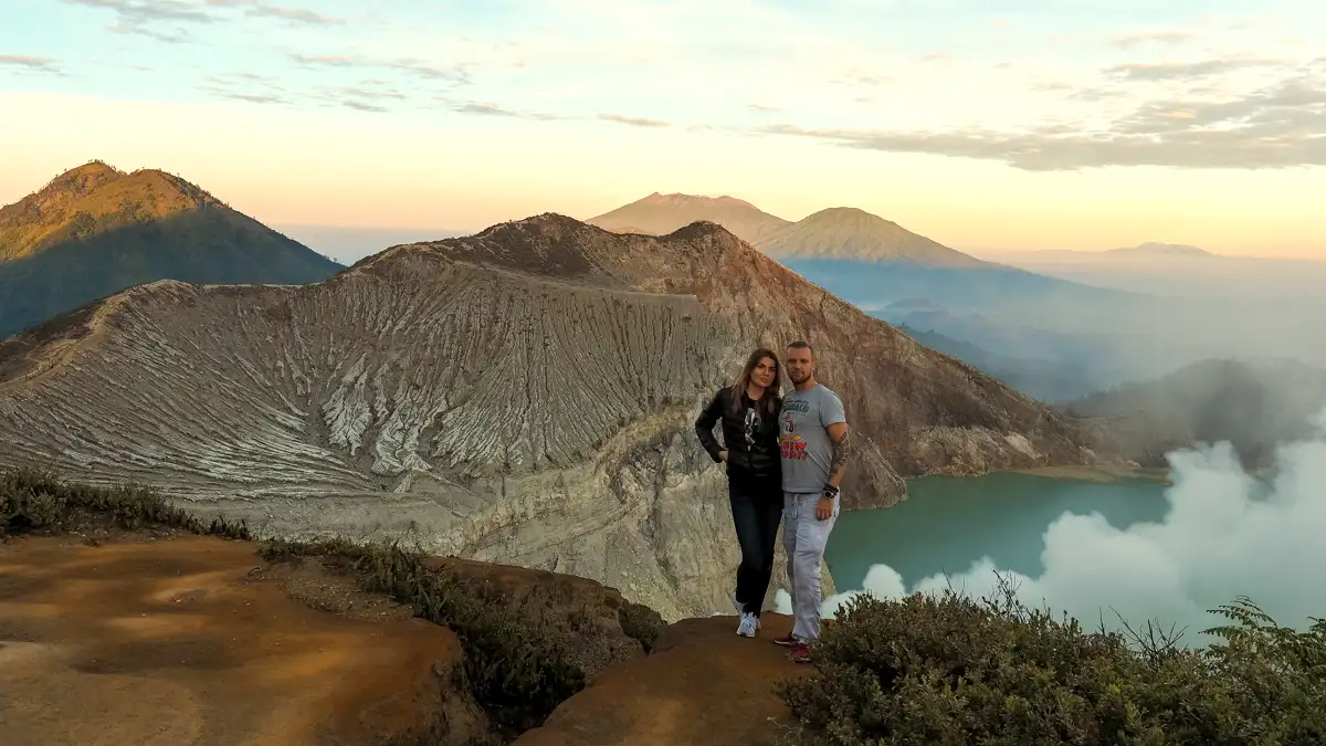 Travelers wearing hiking gear and gas masks at Ijen Crater rim during sunrise